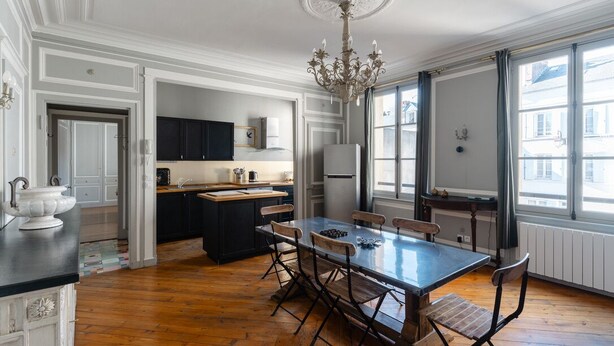 Una cocina amplia con una isla grande, piso de madera y un candelabro.