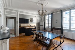Una cocina amplia con una isla grande, piso de madera y un candelabro.