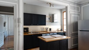 Una cocina moderna con armarios oscuros, encimera de madera y refrigerador de acero inoxidable.