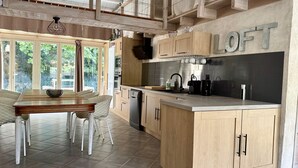 A modern kitchen with wooden cabinets, a central island, and a dining area with a table and chairs. - Gîte "Ile de Ré" with shared 7x7m swimming pool, 20 minutes from the beach (Saint-Coutant-Le-Grand)