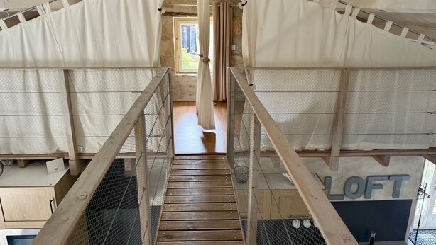 A loft-style room with a wooden staircase, white curtains, and a mesh screen. - Gîte "Ile de Ré" with shared 7x7m swimming pool, 20 minutes from the beach (Saint-Coutant-Le-Grand)
