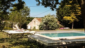 A swimming pool with lounge chairs and a stone building in the background. - Gîte "Ile de Ré" with shared 7x7m swimming pool, 20 minutes from the beach (Saint-Coutant-Le-Grand)
