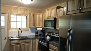 Une cuisine avec des meubles en bois, un réfrigérateur en acier inoxydable, une cuisinière et un four à micro-ondes.