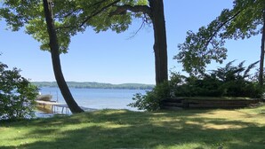 Un foyer circulaire en pierre, avec des bûches et une chaise, situé au bord d’un lac.