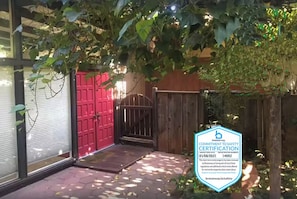 A property with a red door, a gated entrance, and a safety certification badge.