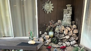 Een aangelegde tuin met potplanten, een decoratieve stenen muur en een houten terras.
