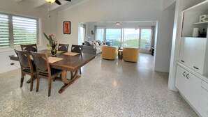 Un vaste espace de vie comprenant une table à manger, des chaises, des canapés et une vue sur la ville.