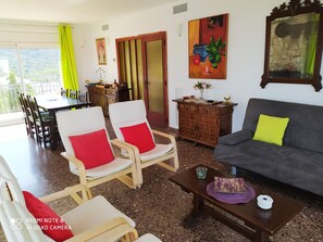 Una sala de estar con comedor, un sofá con un cojín amarillo y un cuadro en la pared.