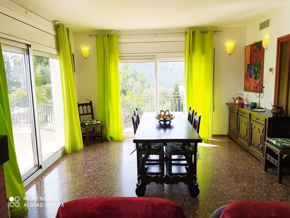 Comedor con mesa, sillas y vistas al verde exterior.