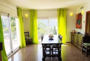 A dining area with a table, chairs, and a view of greenery outside.