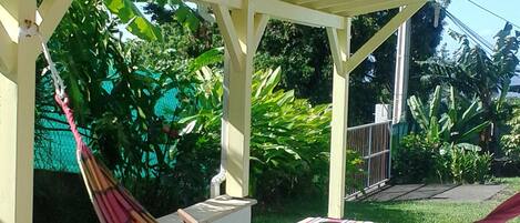 A covered patio with a hammock, a table, and chairs.