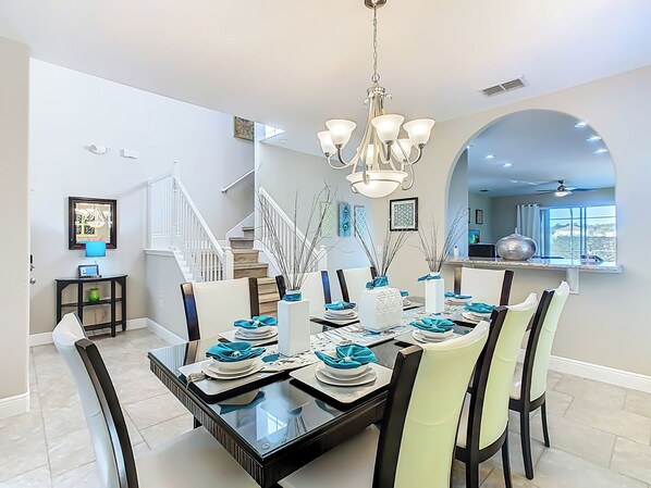 A dining area with a glass table, chairs, and a chandelier. - Villa Peacock: 5 Bed 4.5 bath - Close Resort Centre (Davenport)