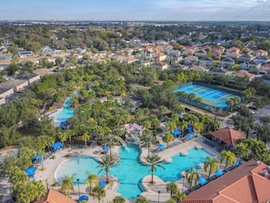 Zona residenziale con una grande piscina circondata da palme e lettini.