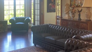 A spacious room with a large leather sofa, a chandelier, and a painting on the wall.