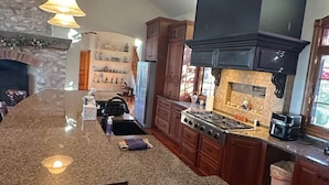 A spacious kitchen with granite countertops, wooden cabinets, and a large island.