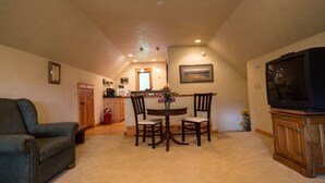 A dining area with a table and chairs, a television, and a sofa in a residential setting. - Mountain View Studio (Bigfork)