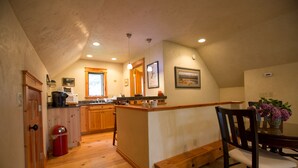 A kitchen with wooden cabinets, a microwave, and a red trash can. - Mountain View Studio (Bigfork)