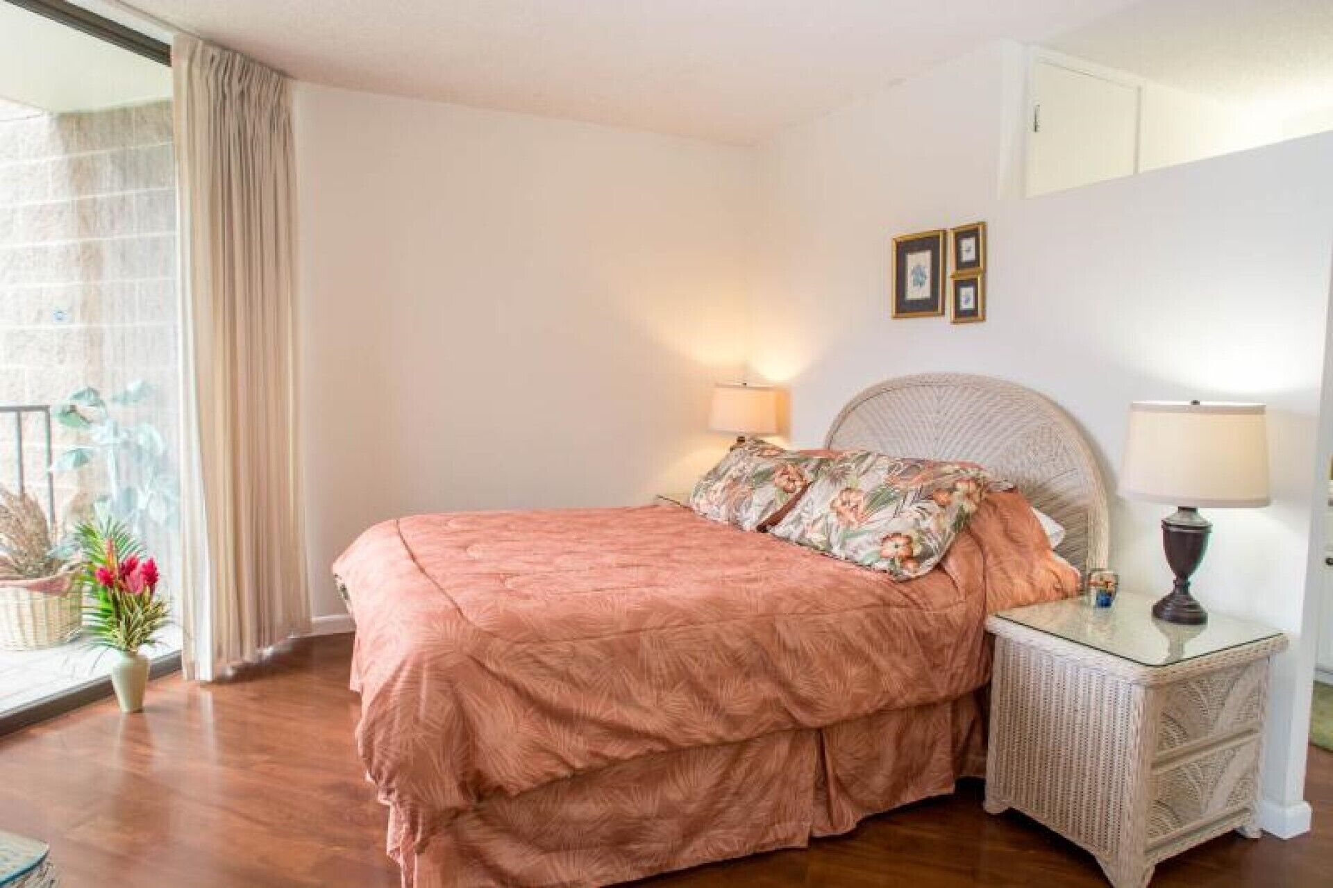 Un dormitorio con cama, mesitas de noche y una ventana con cortinas.