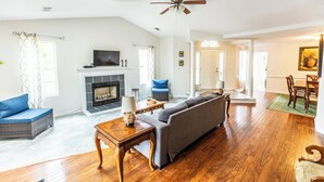 Un salon avec une cheminée, un canapé, une table basse et un ventilateur de plafond.