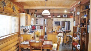 A rustic wooden interior with a dining area, kitchen, and bar. - Mountainside Luxurious/Rustic Log Home~Majestic Views~Prime Location (Livingston)