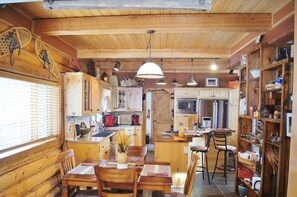 Um interior rústico em madeira com área de jantar, cozinha e bar.