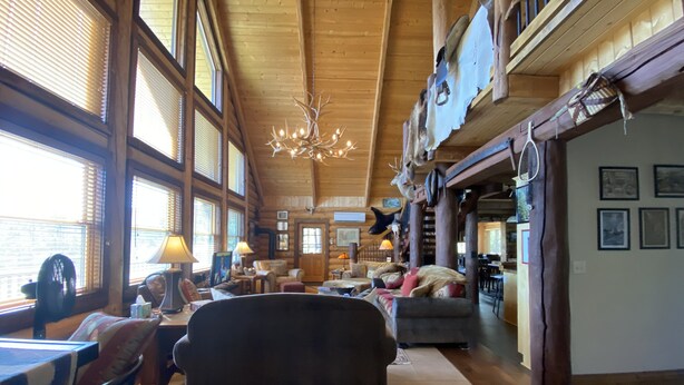 A spacious lodge interior with high ceilings, large windows, and a chandelier. - Mountainside Luxurious/Rustic Log Home~Majestic Views~Prime Location (Livingston)