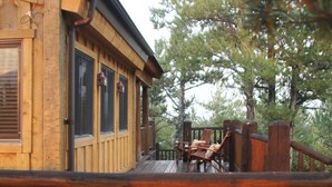 A wooden cabin with a deck, large windows, and a view of trees. - Mountainside Luxurious/Rustic Log Home~Majestic Views~Prime Location (Livingston)