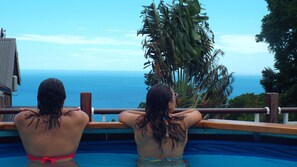 Deux personnes dans une piscine avec vue sur l’océan.
