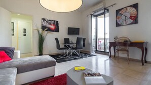 Una sala de estar moderna con un sofá, una mesa de centro, un comedor con sillas, un televisor y un reloj grande en la pared.