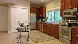 A modern kitchen with wooden cabinets, stainless steel appliances, and a glass dining table. - Spacious house, easy access from Seatac, Seattle & Bellevue.   (Newcastle)