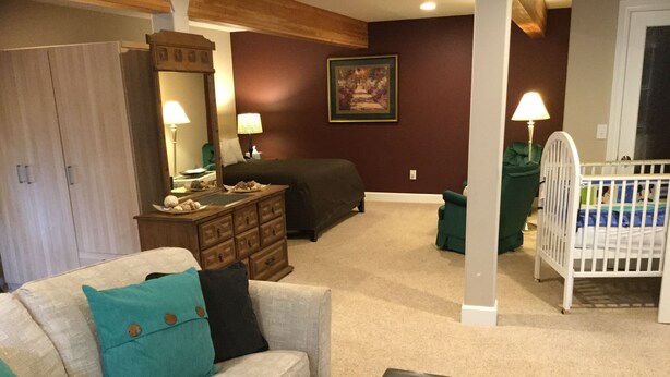 A living room with a sofa, a coffee table, a dresser, a crib, and a painting on the wall. - Spacious house, easy access from Seatac, Seattle & Bellevue.   (Newcastle)