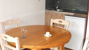 Une petite cuisine équipée d’une table et de chaises en bois, d’un four à micro-ondes, d’une bouilloire et d’un lave-vaisselle.