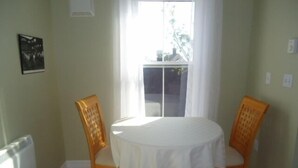 A dining area with a round table and two chairs, a window with curtains, and a radiator on the wall. - Great center of historic districts on Water Street (Charlottetown)
