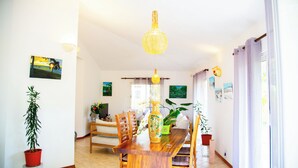 Un comedor con una mesa de madera, sillas, una lámpara colgante y plantas en macetas.
