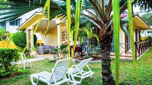 Un patio con sillas de plástico blanco, una mesita y una palmera.