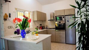 Una cocina moderna con una isla central, armarios de madera, horno empotrado, microondas y refrigerador.
