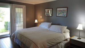 A bedroom with a bed, two bedside lamps, a nightstand, and two framed pictures on the wall.