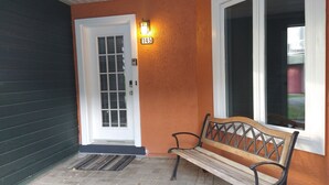 A front porch with a bench, a door, and a window.
