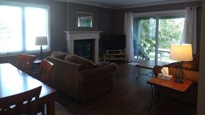 A living room with a fireplace, a television, and a dining area with chairs and a table.