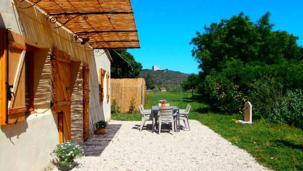 A rustic building with a gravel path leading to a table and chairs set up outside.