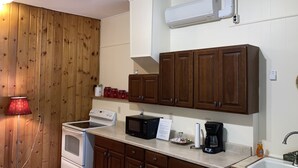 Une cuisine avec des meubles de rangement en bois, une cuisinière, un four à micro-ondes, une machine à café et un évier.