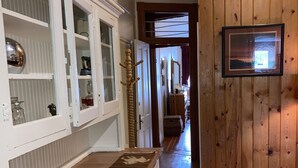 Un couloir doté d’un plancher en bois, d’un tapis à motifs et d’une armoire blanche aux portes en verre.