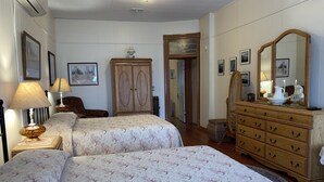 Une chambre avec deux lits, une commode, un miroir et une armoire.