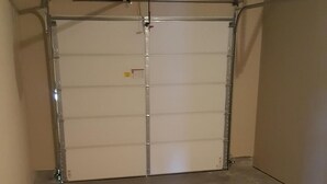 A garage with a closed garage door, concrete floor, and a ceiling-mounted light fixture.