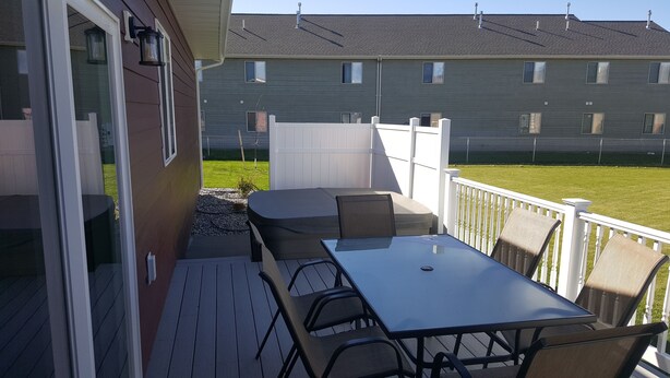 A deck with a table and chairs, a covered seating area, and a view of a residential building in the background.