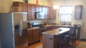 A modern kitchen with a central island, wooden cabinets, and stainless steel appliances.