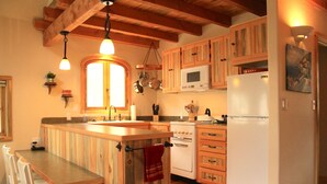 A kitchen with wooden cabinets, a white refrigerator, an oven, and a sink. - Charming Casita With Spectacular River Views  (Riggins)