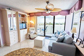 Sala de estar con sofá, sillón, televisor y ventilador de techo.