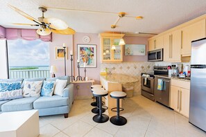 A modern kitchen with a dining area, a ceiling fan, and a view of the outdoors.