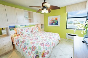 Un dormitorio con cama, ventilador de techo, ventana con vistas y radiador.